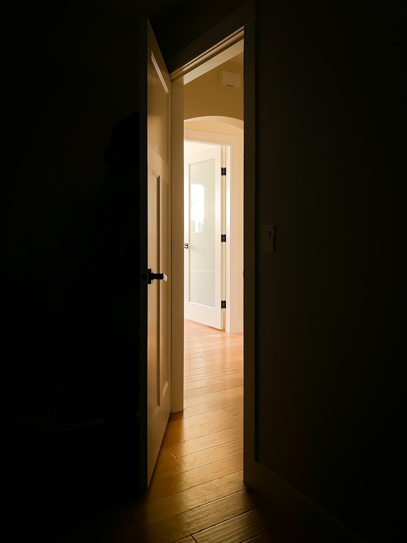 An open front door with daylight spilling onto a hallway floor.